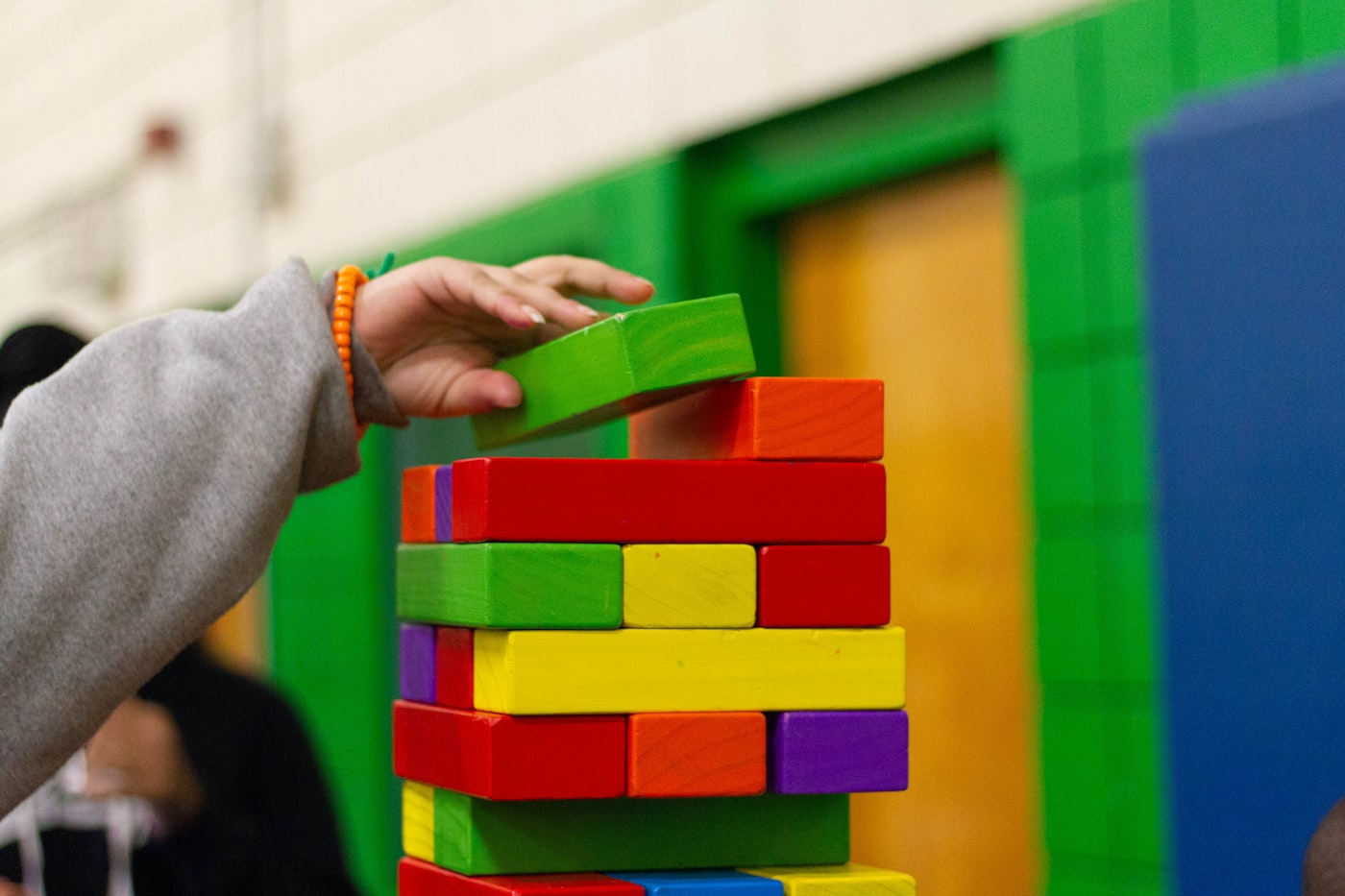 A child's hand stacking colorful building blocks during a play-based learning activity