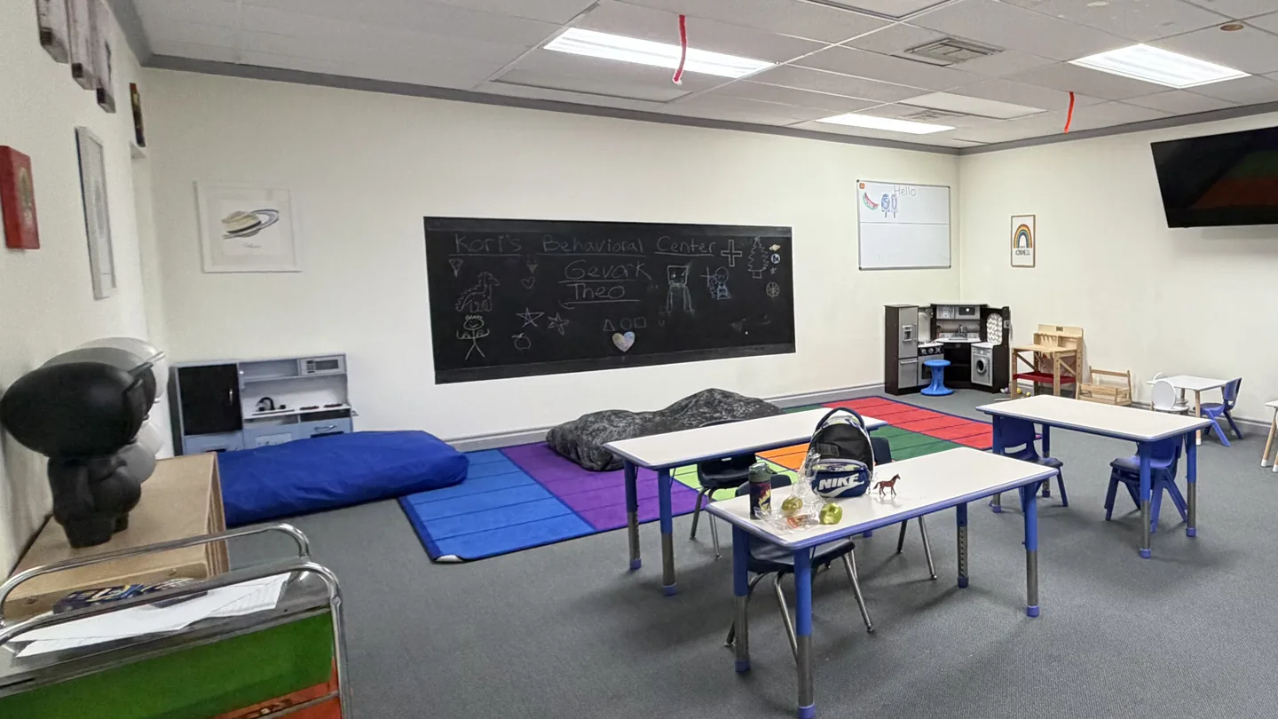 Activity room with play mats, small tables, and a chalkboard at Kori's Glendale center