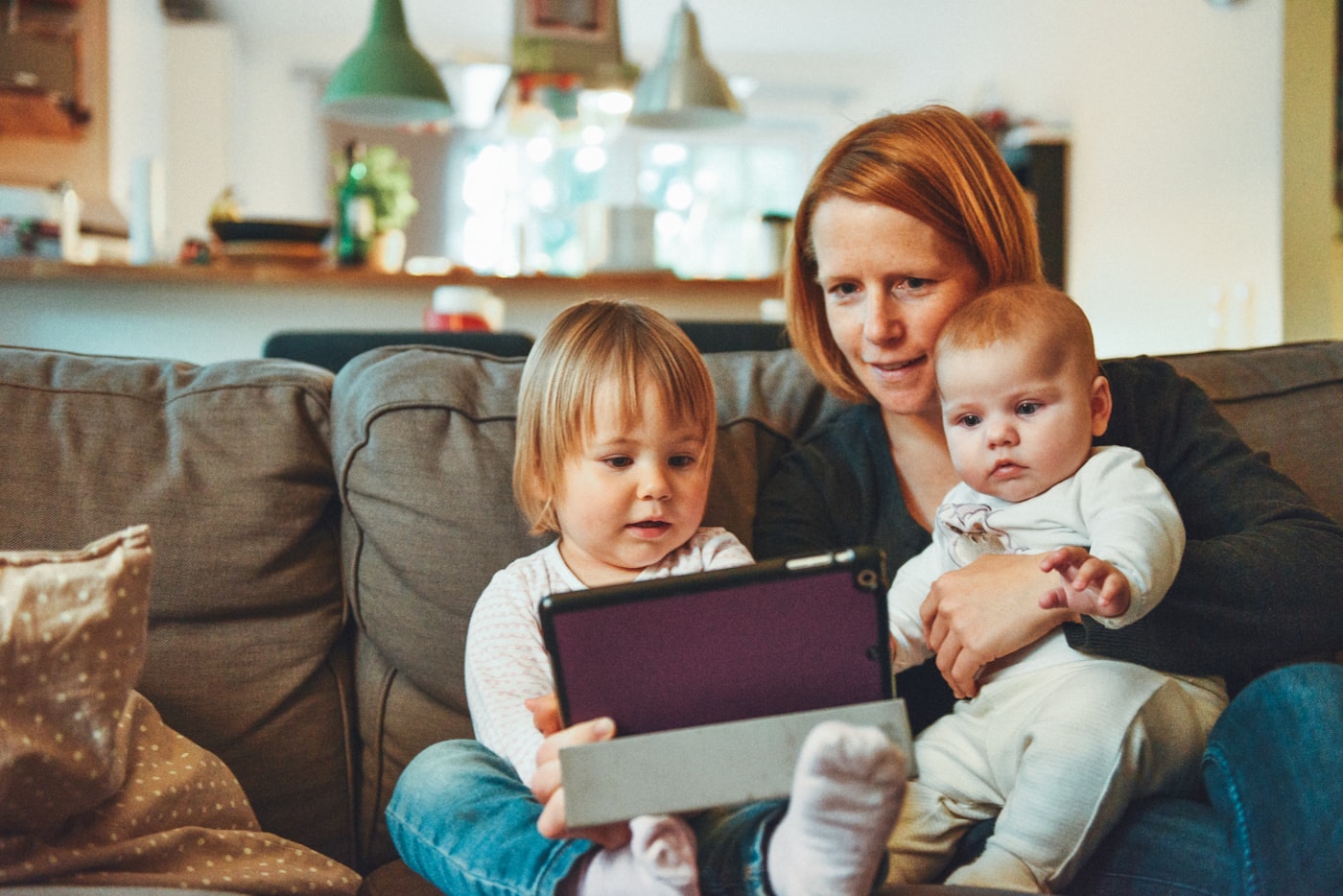 A mother sitting on a couch with her two young children