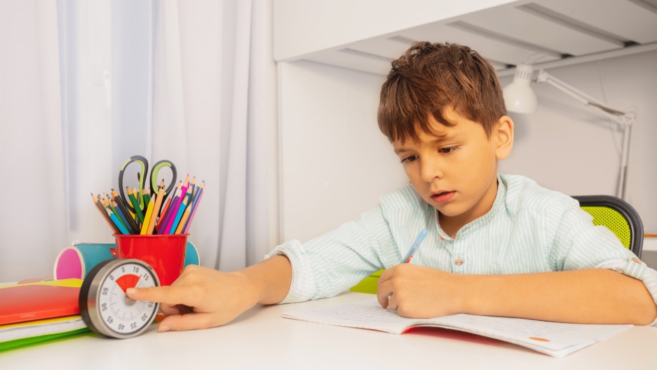 A child practicing a learning activity at a desk with a timer